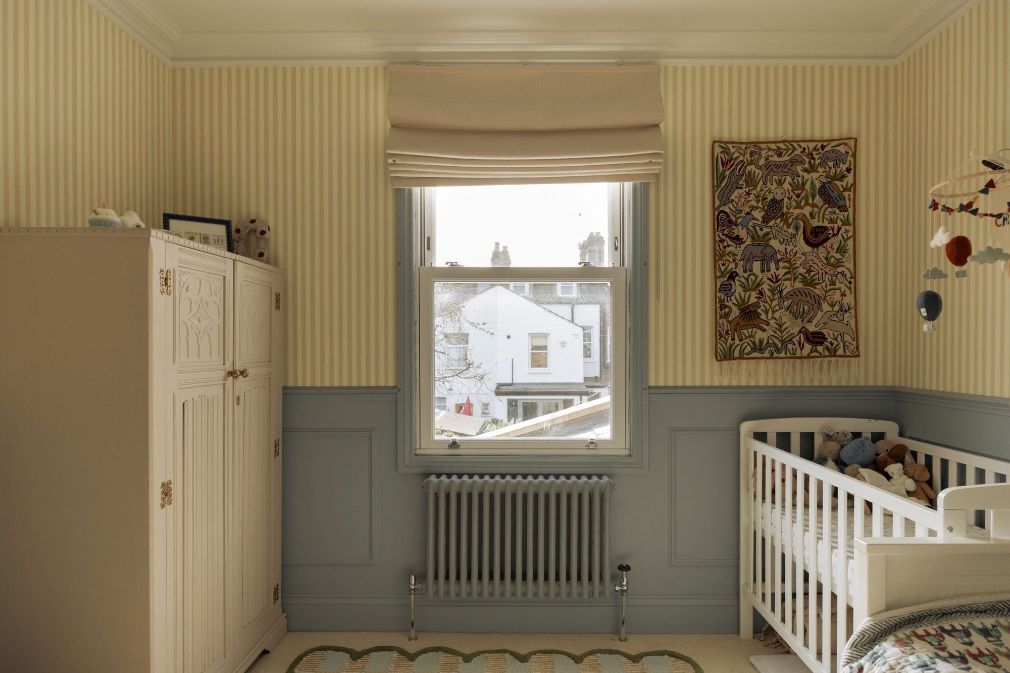Nursery with striped wallpaper and blue-grey panelling