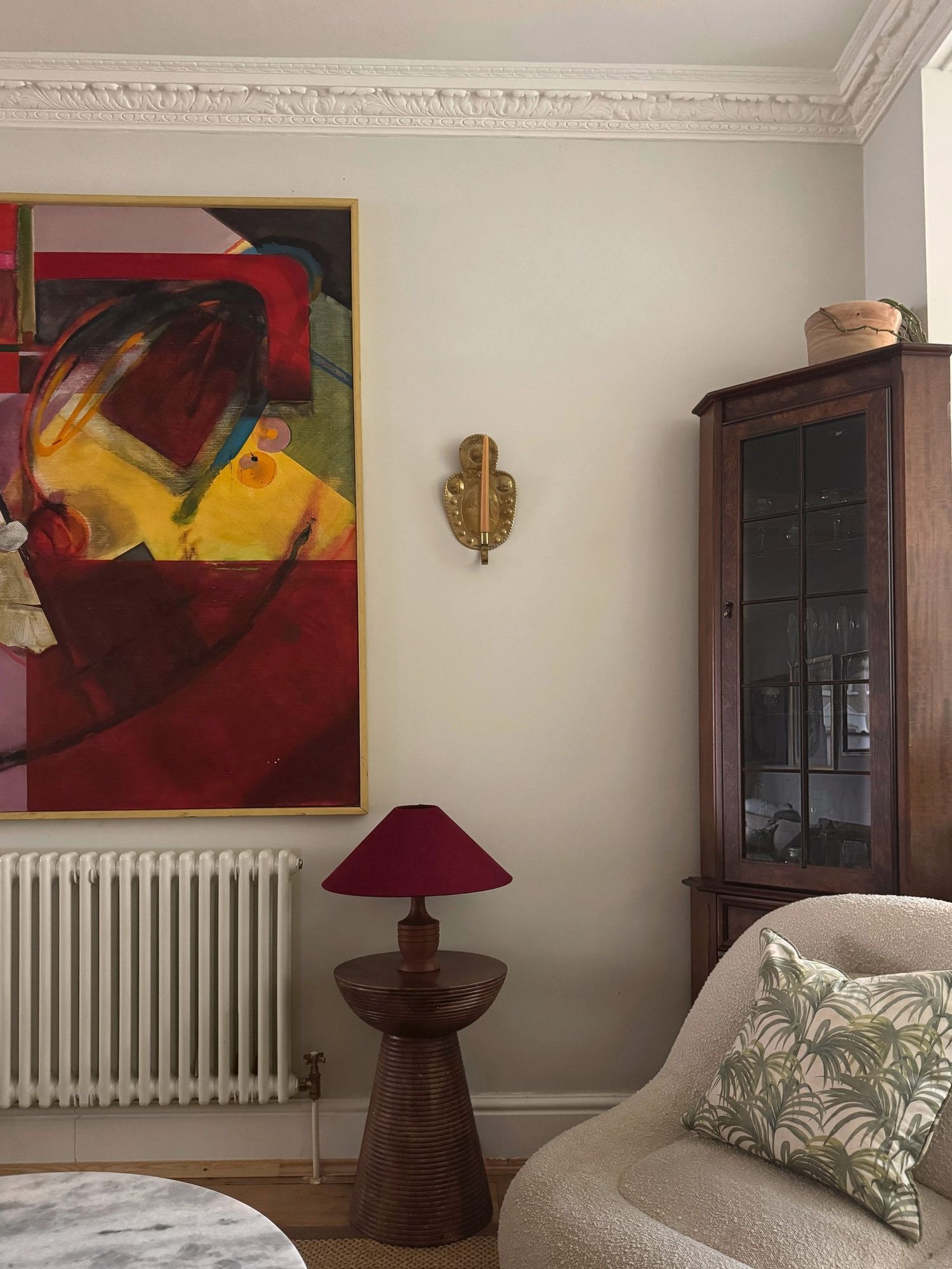Living room with abstract painting, burgundy lamp and boucle chair